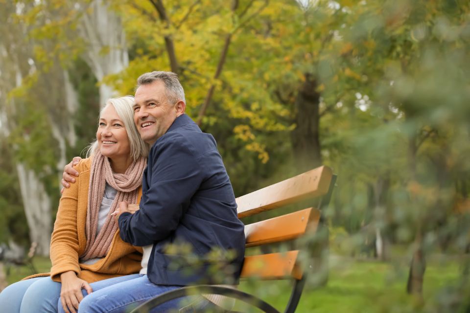 An older couple sitting together on a park bench in North Texas